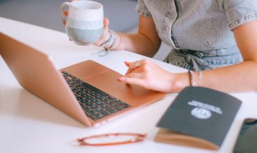 A woman sitting at a table with a laptop and a cup of coffee