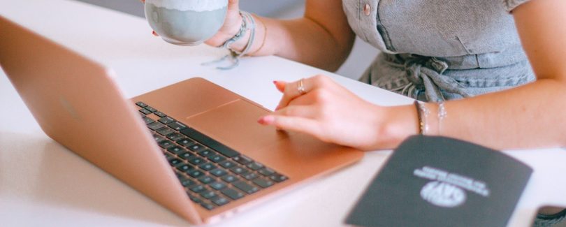 A woman sitting at a table with a laptop and a cup of coffee