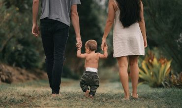 couple walking barefoot with a child at the garden