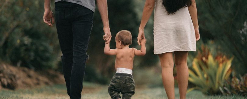couple walking barefoot with a child at the garden