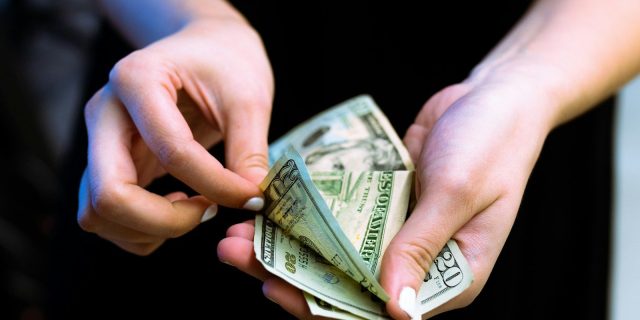 person holding fan of 100 us dollar bill