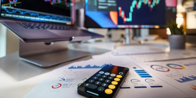 smartphone calculator on desk with financial charts behind